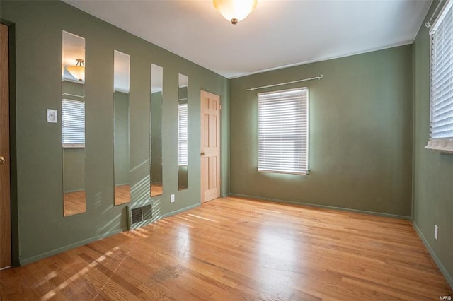 spare room featuring baseboards, light wood-style flooring, and visible vents