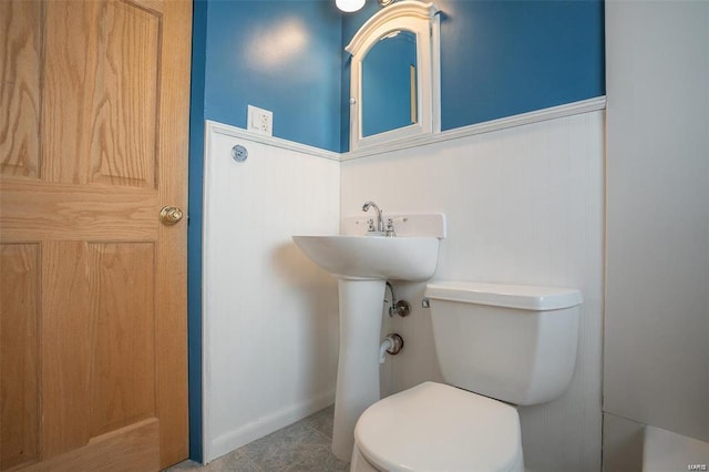 half bathroom with baseboards and toilet