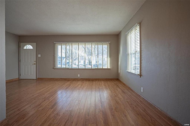 unfurnished living room featuring a textured ceiling, plenty of natural light, and light wood-style flooring