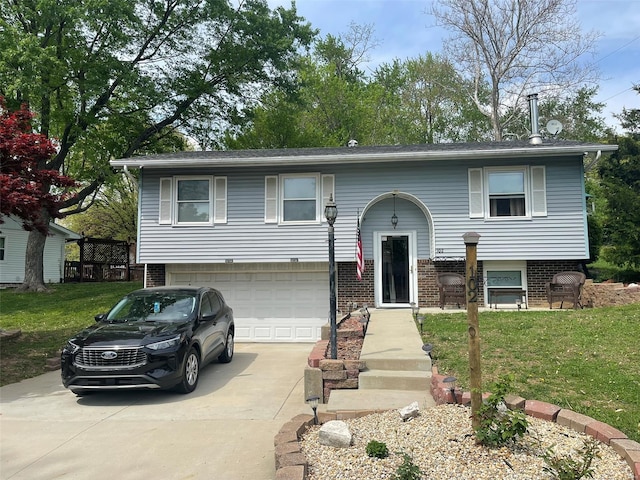 raised ranch with brick siding, a front lawn, concrete driveway, and an attached garage