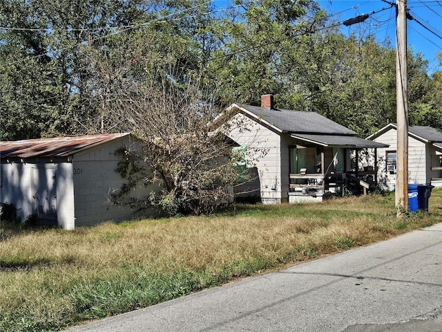 view of side of home featuring covered porch and a chimney