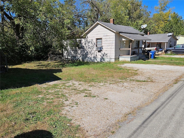 view of side of property featuring a lawn, dirt driveway, and a chimney