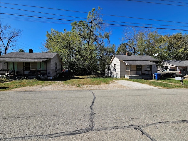 view of front facade with a chimney, a porch, and driveway
