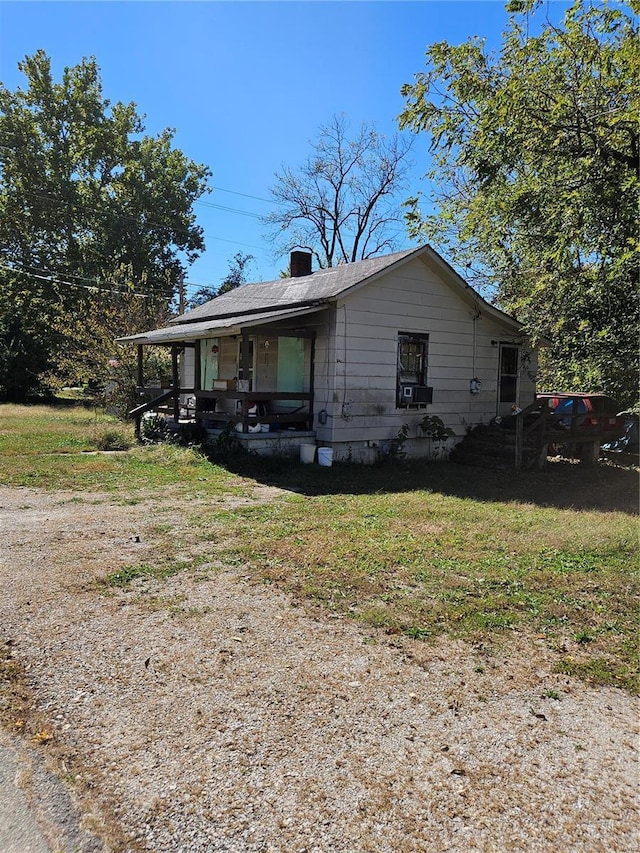 view of front of house with a front lawn, covered porch, and a chimney