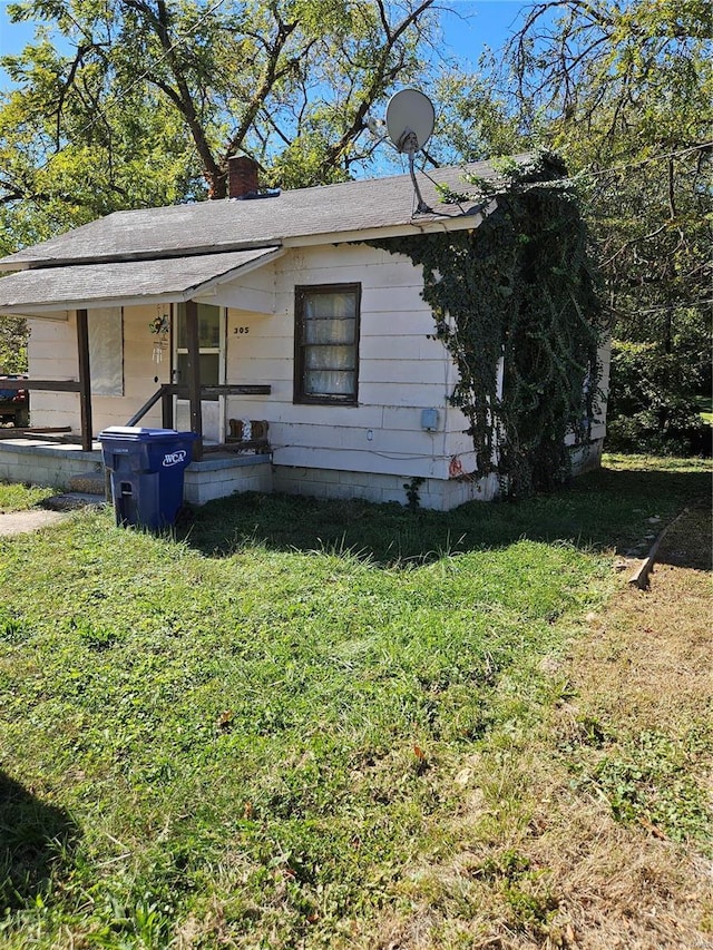 view of front facade with a chimney, covered porch, and a front yard