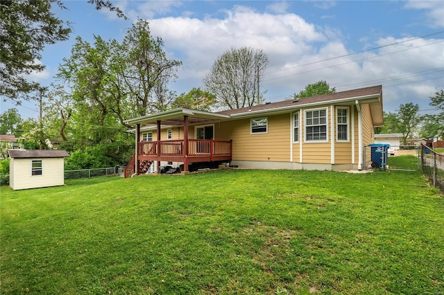 rear view of house featuring a lawn, a fenced backyard, a wooden deck, and an outbuilding