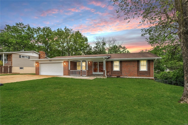 ranch-style home with brick siding, a garage, a front yard, covered porch, and driveway