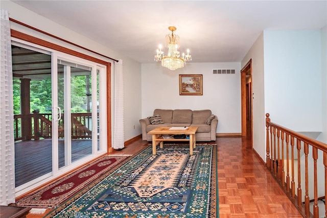 living area with baseboards, visible vents, and an inviting chandelier