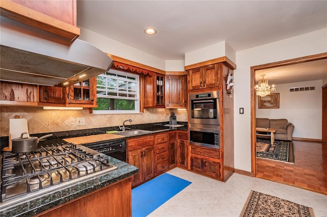 kitchen with decorative backsplash, appliances with stainless steel finishes, a sink, an inviting chandelier, and extractor fan