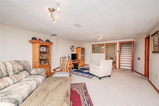 living area featuring baseboards, visible vents, a textured ceiling, and light colored carpet