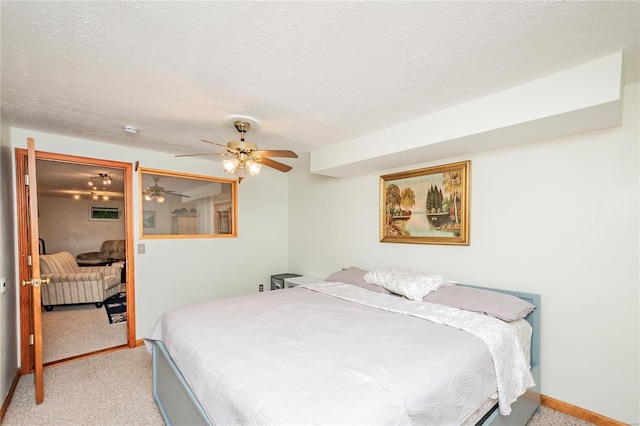 bedroom featuring a textured ceiling, ceiling fan, and light carpet