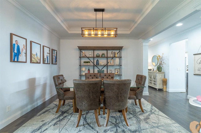 dining space featuring baseboards, a raised ceiling, ornamental molding, and wood finished floors