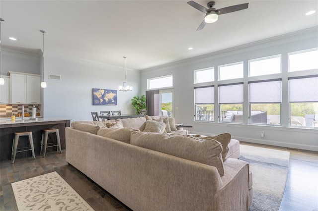 living room with visible vents, dark wood-style floors, recessed lighting, ornamental molding, and ceiling fan with notable chandelier