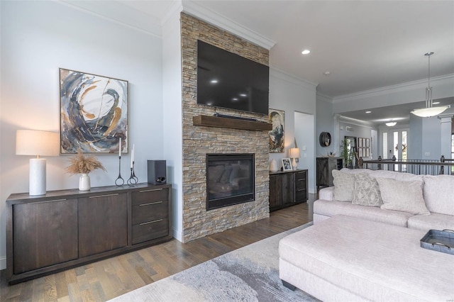 living room with baseboards, ornamental molding, a stone fireplace, and wood finished floors