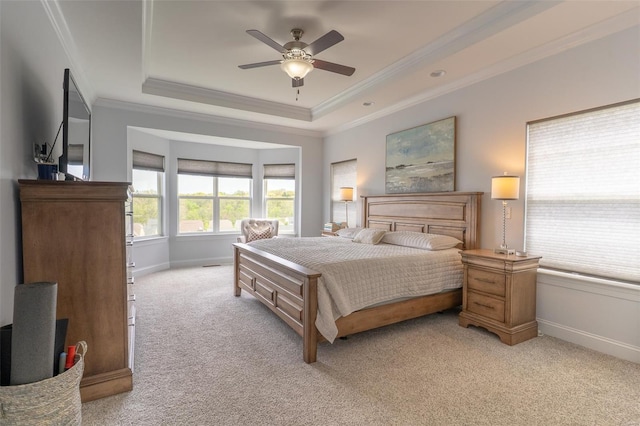 bedroom with baseboards, crown molding, light colored carpet, and a tray ceiling