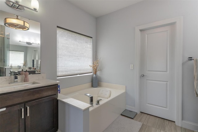 bathroom featuring a garden tub, vanity, and baseboards