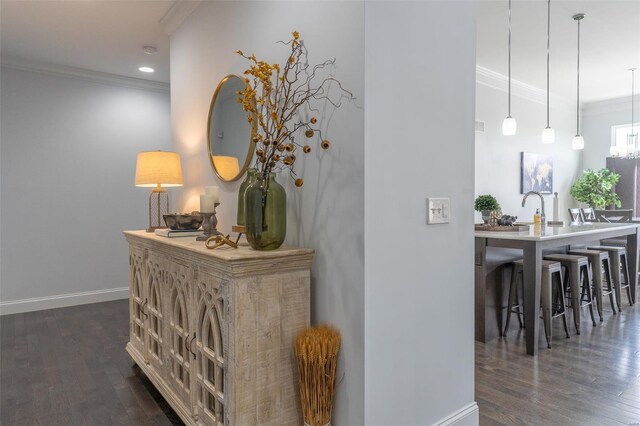 corridor with a chandelier, baseboards, ornamental molding, and dark wood-style flooring