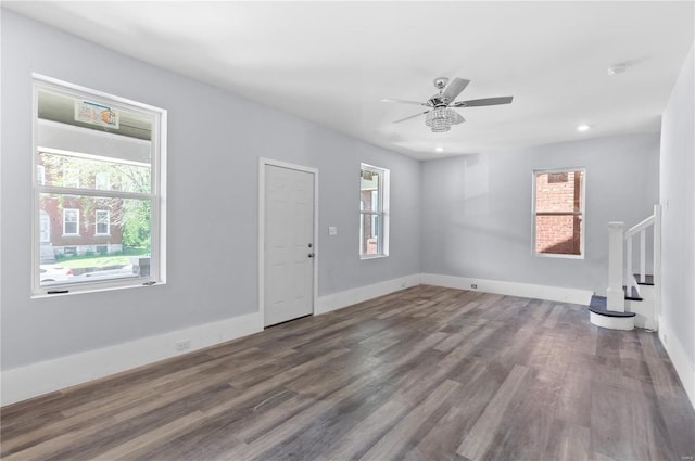 unfurnished living room with baseboards, stairway, wood finished floors, and a ceiling fan