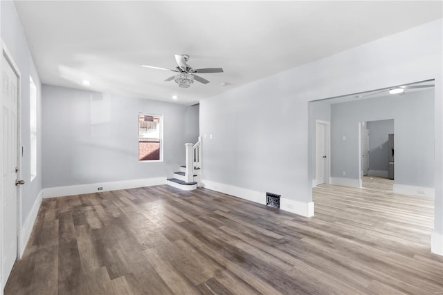 unfurnished room featuring stairs, ceiling fan, wood finished floors, and visible vents