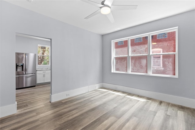 spare room featuring ceiling fan, baseboards, and light wood-type flooring