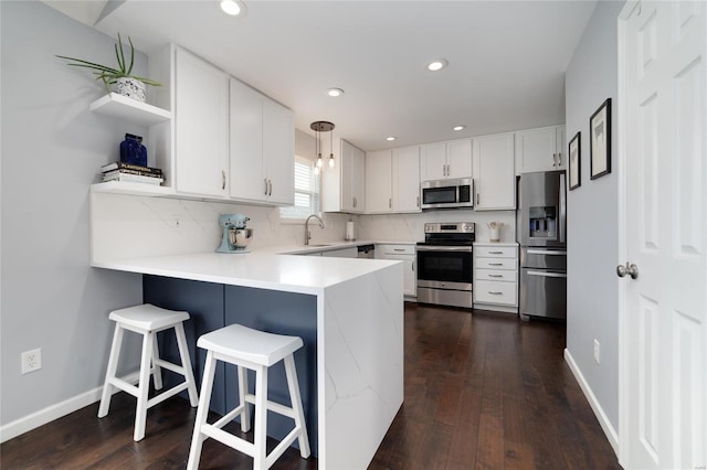 kitchen with appliances with stainless steel finishes, open shelves, light countertops, a peninsula, and white cabinetry