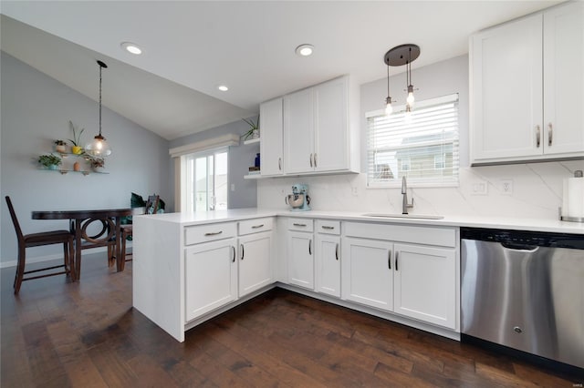 kitchen featuring a sink, a peninsula, backsplash, stainless steel dishwasher, and vaulted ceiling