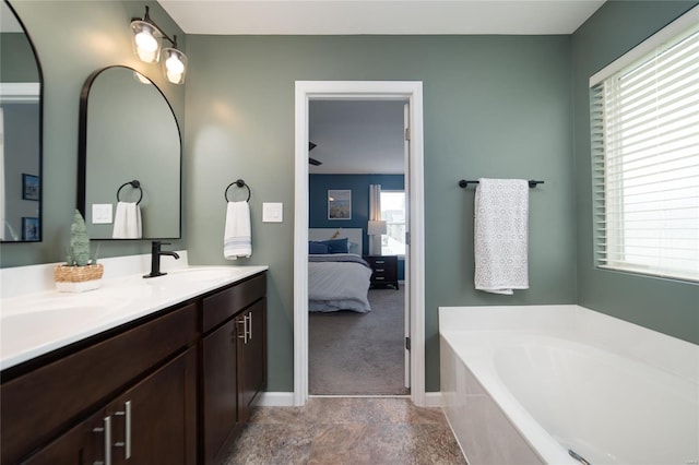 ensuite bathroom with double vanity, a bath, a sink, baseboards, and ensuite bathroom