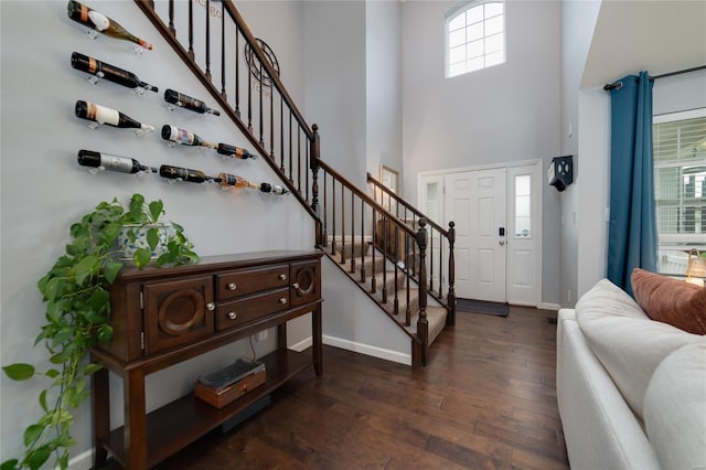 entrance foyer with baseboards, dark wood finished floors, stairway, and a towering ceiling