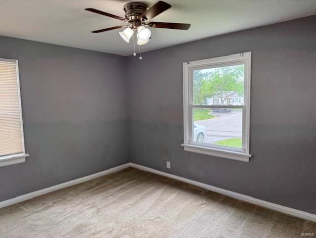 carpeted empty room featuring baseboards and ceiling fan