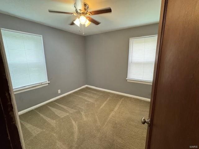 carpeted spare room with baseboards and a ceiling fan