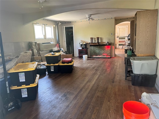 living room featuring arched walkways, a ceiling fan, wood finished floors, and cooling unit