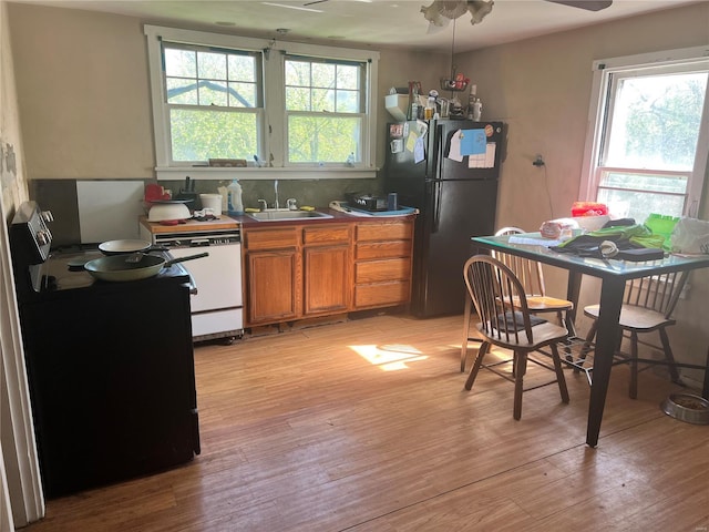 kitchen with freestanding refrigerator, a sink, brown cabinets, and a healthy amount of sunlight