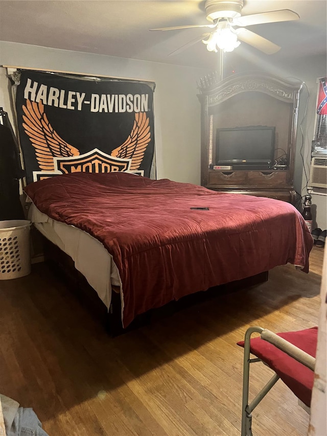 bedroom with ceiling fan, wood finished floors, and cooling unit