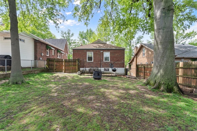 back of property featuring brick siding, a fenced backyard, and a yard