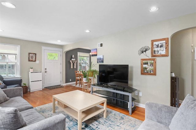 living area featuring arched walkways, recessed lighting, wood finished floors, and visible vents