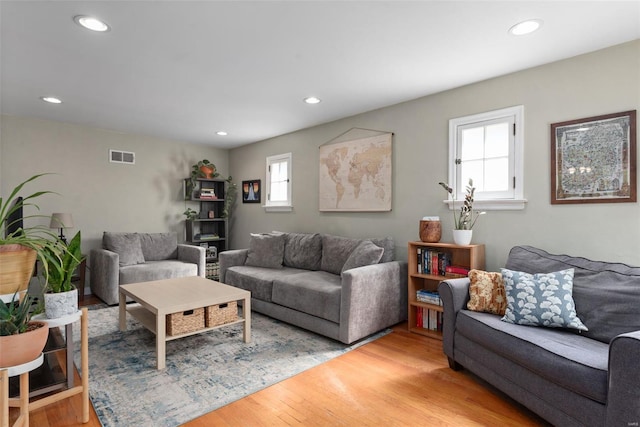 living room with recessed lighting, visible vents, and light wood finished floors
