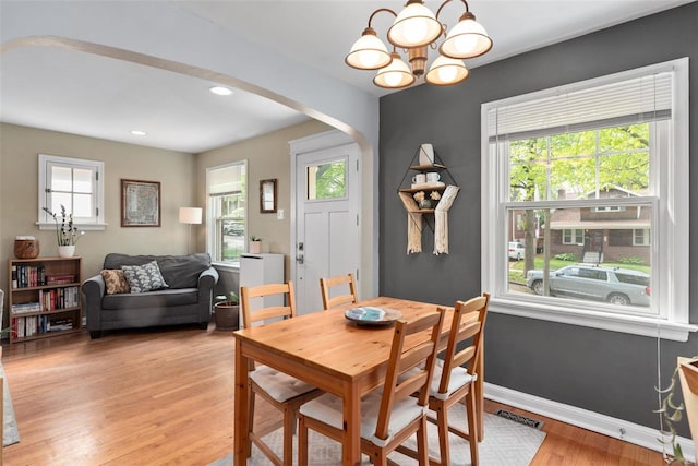 dining area with arched walkways, baseboards, a chandelier, light wood-style floors, and recessed lighting