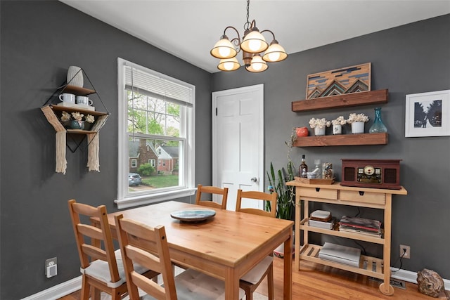 dining space featuring baseboards, a notable chandelier, and wood finished floors
