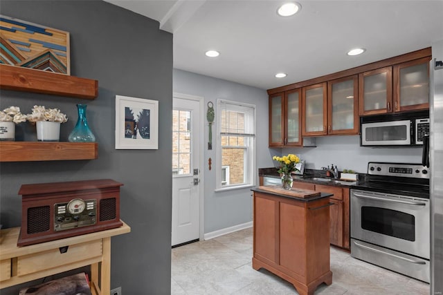 kitchen with dark countertops, a center island, recessed lighting, a sink, and stainless steel appliances