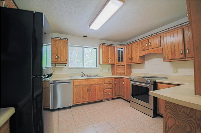 kitchen featuring brown cabinets, appliances with stainless steel finishes, light countertops, and a sink