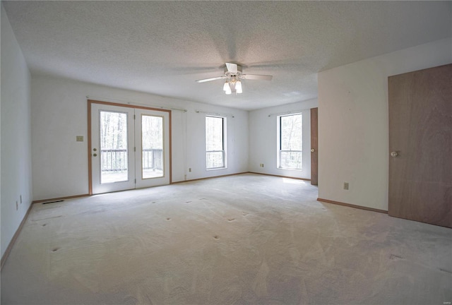 unfurnished room featuring baseboards, ceiling fan, a textured ceiling, and light colored carpet