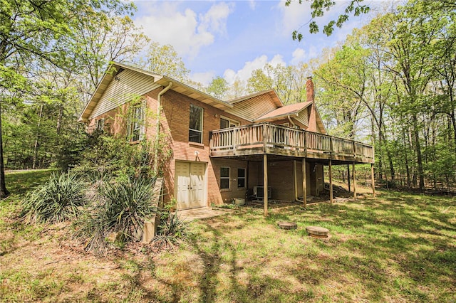 rear view of house featuring a lawn, a deck, a chimney, and brick siding