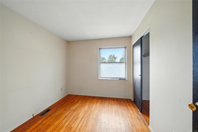 unfurnished bedroom featuring a closet, baseboards, visible vents, and light wood-style floors