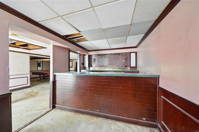 bar featuring a dry bar, wainscoting, concrete floors, and a paneled ceiling