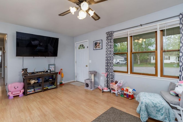 rec room featuring baseboards, wood finished floors, and a ceiling fan