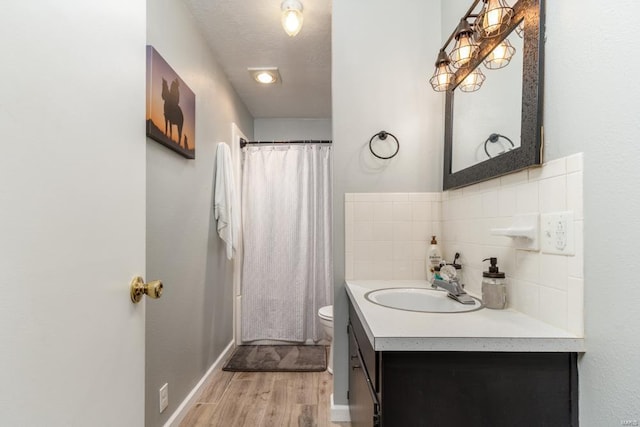 bathroom featuring tasteful backsplash, wood finished floors, toilet, vanity, and curtained shower
