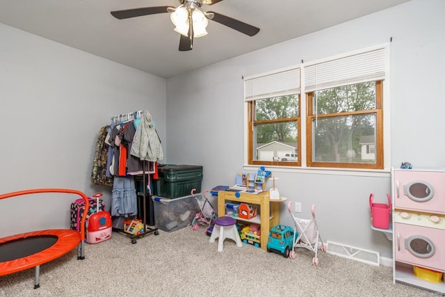 rec room featuring carpet flooring, stacked washer / drying machine, visible vents, and ceiling fan