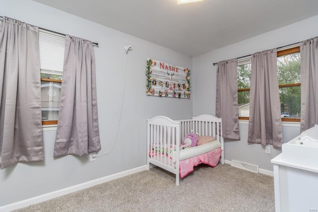 carpeted bedroom with visible vents, a crib, and baseboards