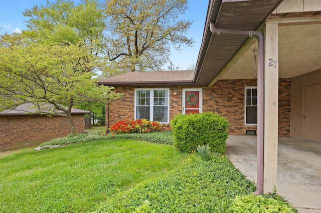 view of side of property with brick siding and a lawn