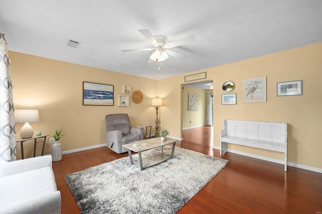 living room with wood finished floors, visible vents, a ceiling fan, and baseboards